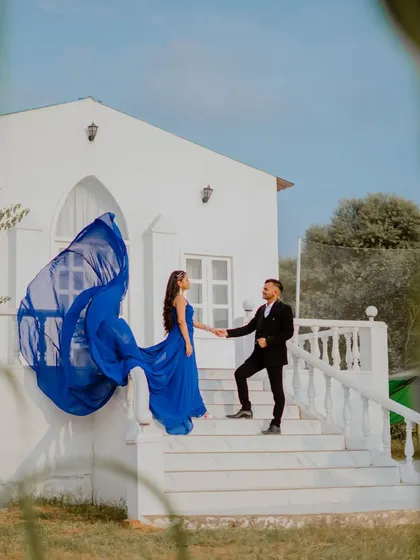 The bride's royal blue gown flows beautifully from the steps of the white chapel set. This shot is all about elegance, drama, and creating a fairytale moment.