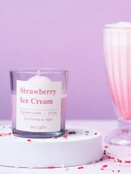 A styled shot of a Strawberry Ice Cream scented candle from Delight Candles, paired with a matching milkshake. This creative concept clearly communicates the candle's fragrance.