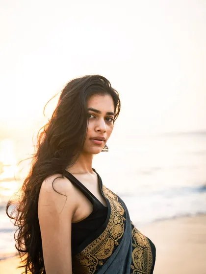 A close-up portrait focusing on the model's expression, with the soft, out-of-focus sea and sky creating a clean and beautiful background.