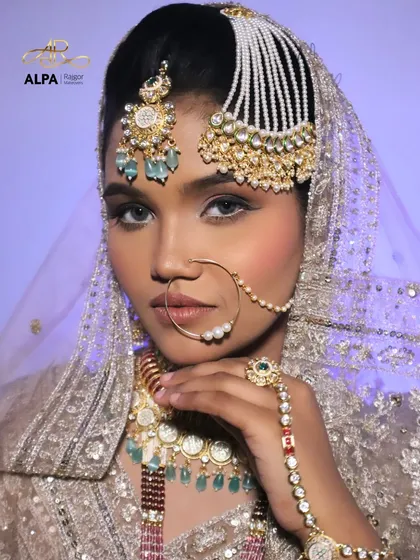 A striking pose that showcases the stunning passa (jhoomar) and the flawless airbrushed-finish makeup. The eyes are kept soft to balance the heavy jewelry.
