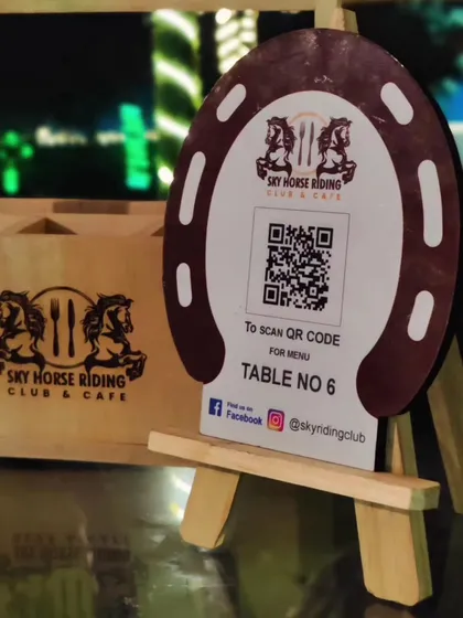 Even the small details are part of the experience. Our cafe tables feature these custom horseshoe-shaped stands with a QR code for easy menu access, blending rustic charm with modern convenience.