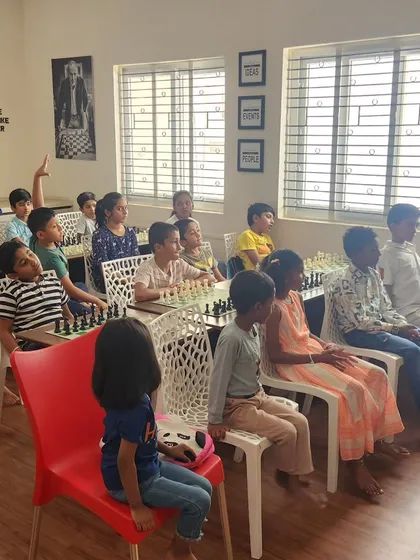 A classroom full of attentive students listening to a lesson. One student raises her hand, showing the interactive and participatory nature of our coaching sessions.