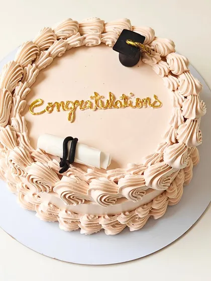 A simple yet elegant cake to celebrate a graduation. It features a fondant graduation cap and diploma, with "Congratulations" written in gold script.