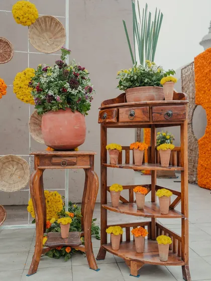 A charming decor corner with rustic wooden furniture and pots of fresh marigolds, adding to the warm and festive ambiance of the Haldi ceremony.