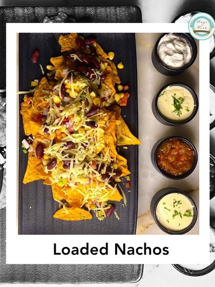 Our Vegetarian Loaded Nachos are a delicious Mexican appetizer. Tortilla chips are topped with beans, veggies, and cheese, served with a variety of dips.