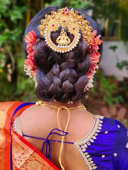 A multi-braided khopa bun for a traditional Marathi wedding. This intricate hairstyle is a statement piece, beautifully accessorized with a temple-style hair brooch.