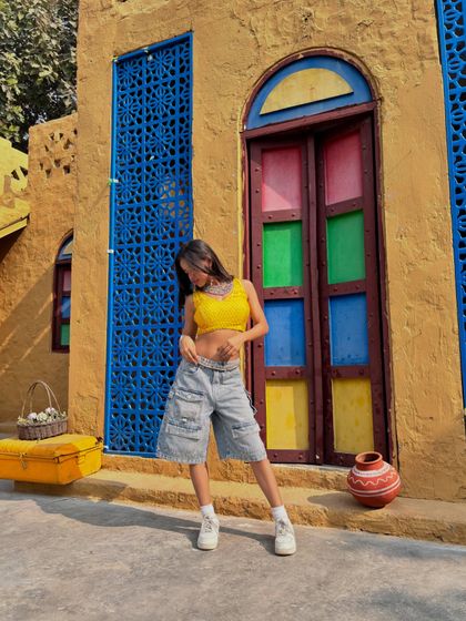 A full-length view of the Indo-western outfit against the vibrant yellow and blue wall.