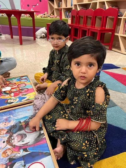 Dressed in their festive best for Diwali. Here, two children are working together on a puzzle, enjoying a quiet moment of play amidst the celebrations.