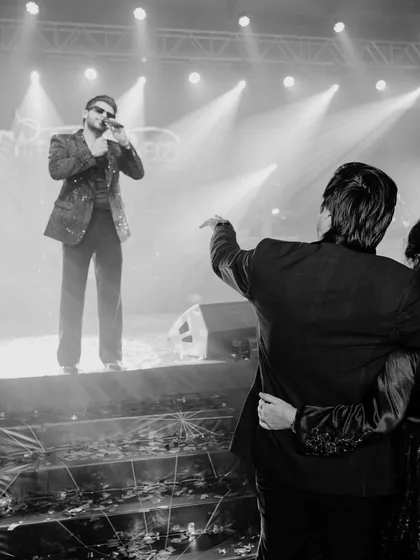 A black and white shot of a live performance at the afterparty, capturing the concert-like energy and dramatic stage lighting that defined the night.