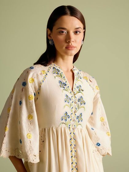 A close-up of a beautiful off-white dress with delicate blue and yellow floral embroidery, perfect for a summer day.