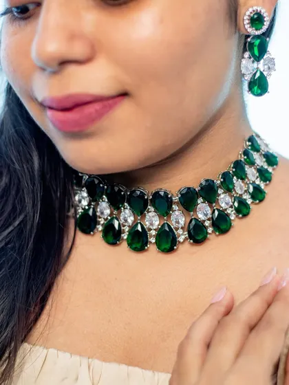 A close-up of a bold and beautiful emerald and zircon choker. This piece is designed to be the star of the show, perfect for pairing with a simple gown or a chic cocktail dress.
