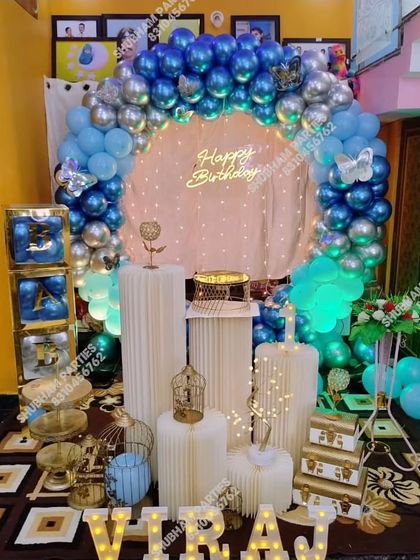 An elaborate blue and silver chrome balloon arch with multiple props and marquee letters for a grand birthday celebration at home.