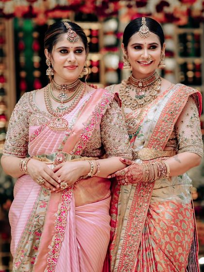 A lovely photo of two sisters in their coordinated sarees, showcasing the rich fabrics and detailed embroidery that are hallmarks of our studio.
