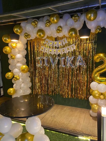 A close-up of the 'JIVIKA' name balloons and the gold shimmer backdrop.