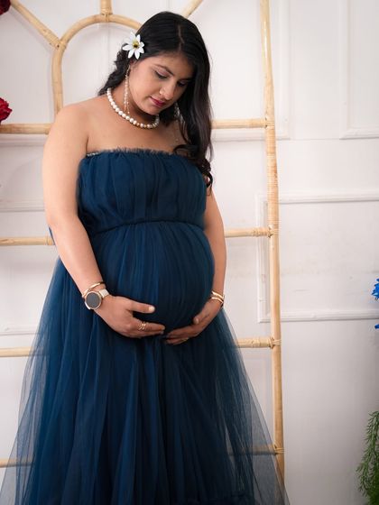 A quiet, reflective moment captured during a maternity session. The mother-to-be looks down at her bump with love, a simple pose that speaks volumes.