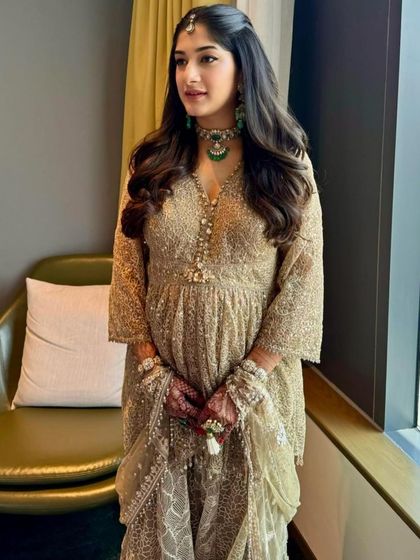 A quiet, poised moment by the window, showing the intricate details of her outfit and the soft, natural makeup.