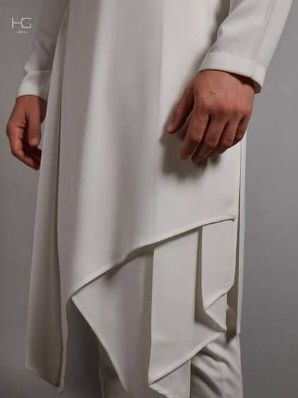 A close-up on the layered, cascading drape of the white kurta, showcasing the fluid movement and expert pattern-making.