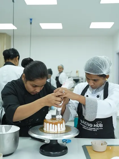 We believe in 100% hands-on learning. Here, I am guiding a student to perfect her piping technique on a caramel drip cake. You get personal attention to ensure you master every skill, from holding the piping bag correctly to creating beautiful, stable decorations.