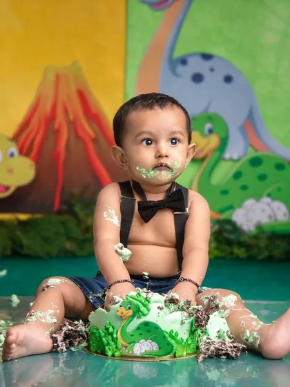 This little dino fan is having a messy but delicious time with his prehistoric-themed cake. The look of pure satisfaction says it all.
