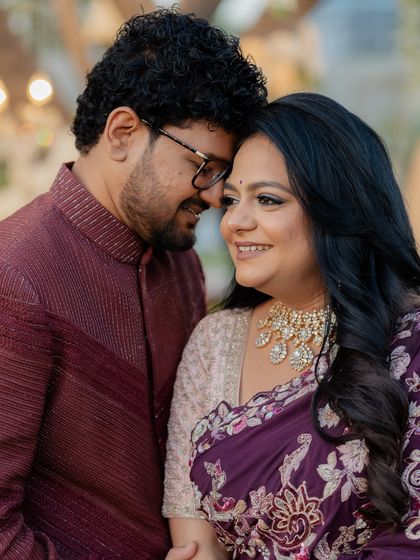 A close-up of the couple's reception look, highlighting the intricate embroidery on the bride's saree and the groom's textured bandhgala.