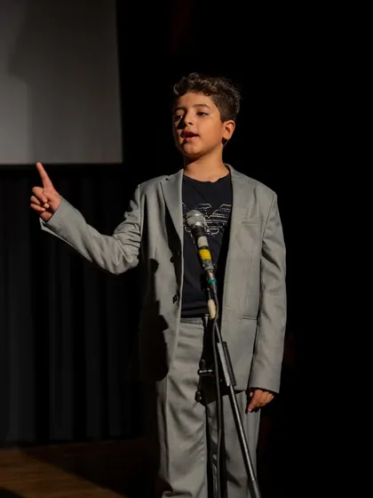 A young actor in a suit delivering a speech. This demonstrates how theatre skills are directly applicable to formal public speaking.