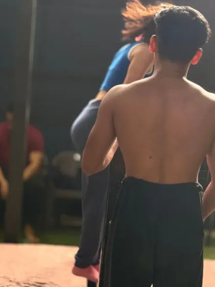 A coach providing support during a bar exercise. This allows the athlete to build confidence and strength.