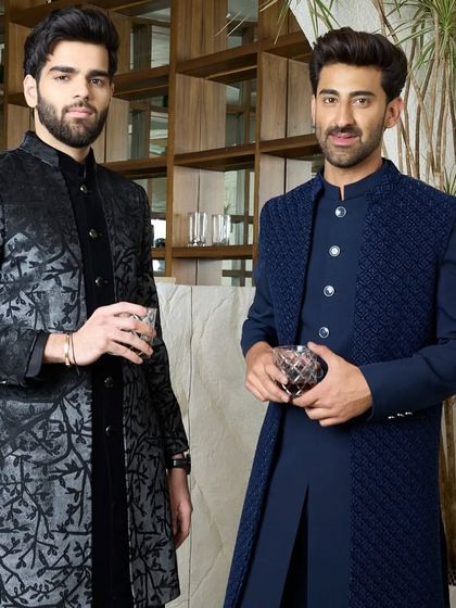 Two examples of evening elegance. On the left, a black kurta with a subtle, shimmering pattern, and on the right, a navy blue layered Indo-Western set with a textured jacket.