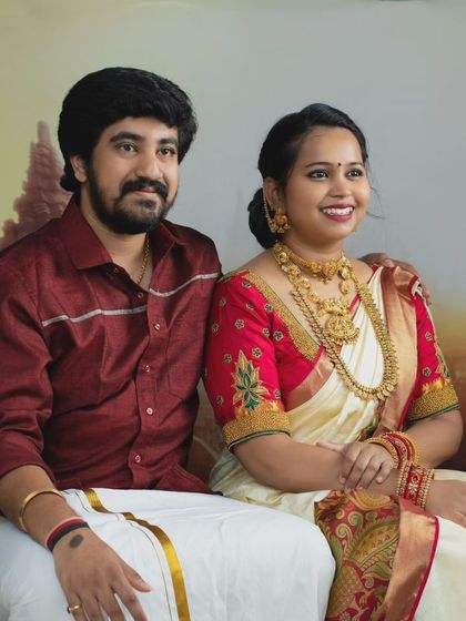 A beautifully composed portrait of a couple in traditional South Indian attire, seated against a backdrop of ancient temple ruins.