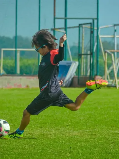 A player in mid-kick, striking the ball with power and precision during a Pride Cup game.
