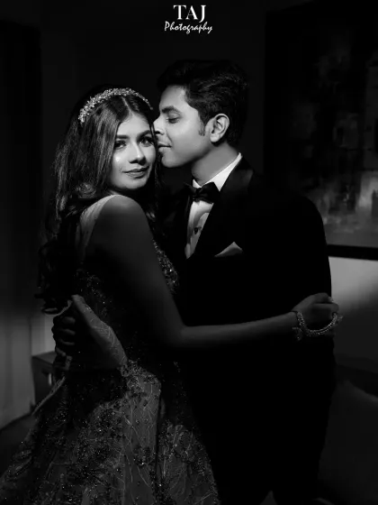 A classic and intimate black and white portrait. The groom whispers in the bride's ear as she looks towards the camera, creating a shot that is both romantic and engaging.