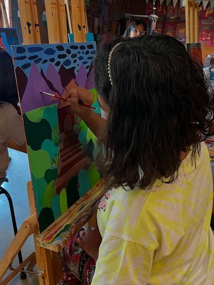 This student uses a range of greens and purples to create rolling hills, showing her interpretation of Hockney's approach to landscape and color.