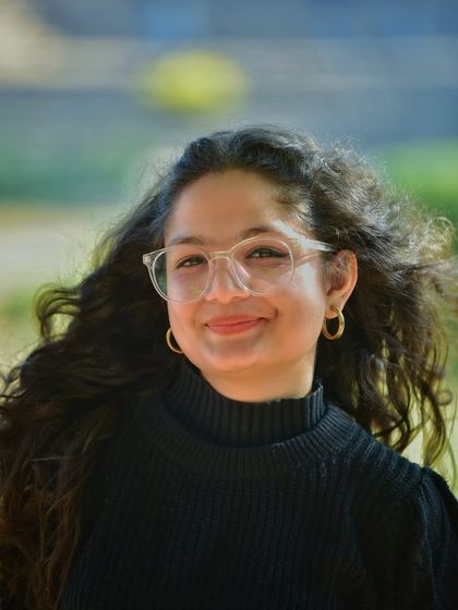 A close up portrait that beautifully captures her smile and curly hair. The soft, blurry background makes her happy expression the main focus of the shot.