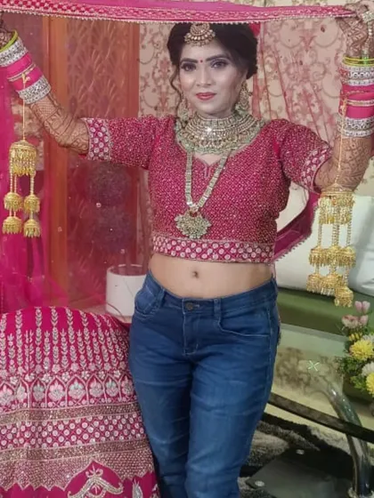 Capturing the fun, behind the scenes moments of a bride getting ready. Here she is, all smiles with her bridal makeup, hair, and jewelry on, ready to slip into her lehenga for the big day.