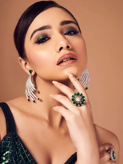 A bold and confident pose. The dark, smoky eye and glossy nude lip create a balanced look that is both dramatic and chic.