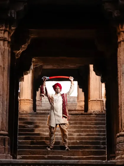 A powerful solo portrait of the groom in a heritage setting. Standing on the steps of the haveli with a sword, this shot has a majestic and commanding presence, fit for a king.