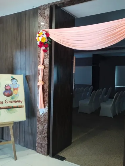A welcoming entrance for a naming ceremony. The doorway is decorated with drapes and flowers, complemented by a custom welcome sign on an easel.