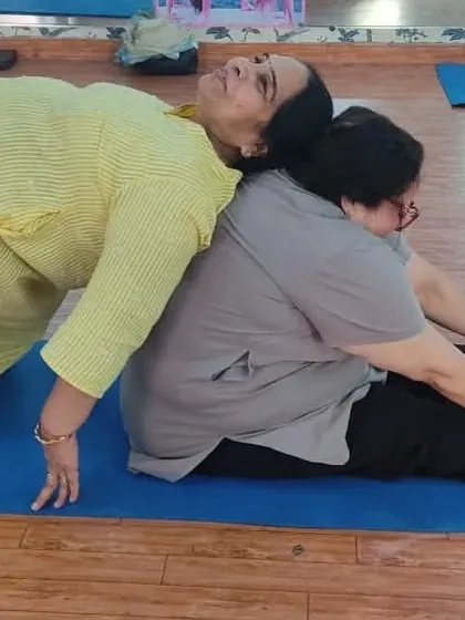 This image captures a beautiful moment of support and connection. One client performs Setu Bandhasana (Bridge Pose) while her partner provides a stable base in a forward fold, creating a mutually beneficial stretch.