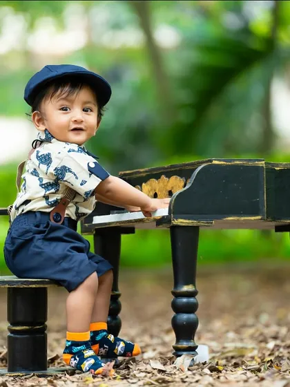 Taking the piano outdoors. This little musician is enjoying a session in the park, combining a classic prop with beautiful natural surroundings.