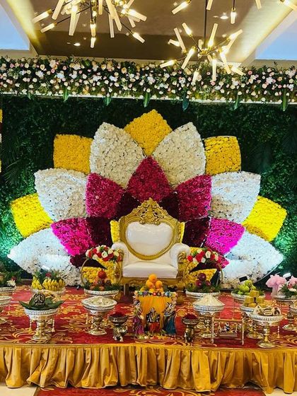 A stunning lotus-inspired backdrop made from petals of colorful flowers. This artistic design creates a grand and memorable setting for a Seemantham, with a full display of offerings in front.