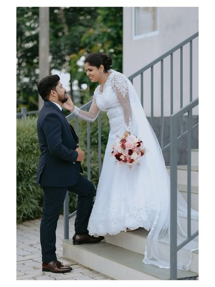 A tender moment on the stairs, showcasing the beautiful lace details of the bride's gown and the connection between the couple.