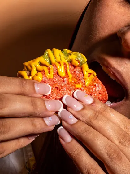 A close-up, personal shot of someone about to take a bite of a taco. This lifestyle approach makes the food feel relatable and desirable.