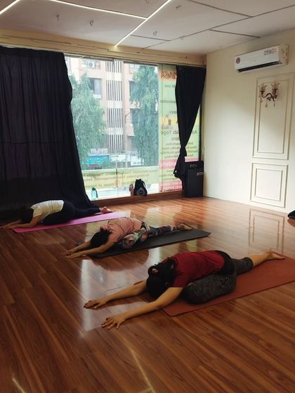 Students holding a deep stretch in Pigeon Pose. This asana is fantastic for releasing tight hips, something we focus on to counteract the effects of sitting all day.
