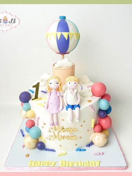 A sweet hot air balloon adventure for twins Manya and Moram's first birthday. This cake features two adorable fondant figures, colorful balloons, and a whimsical theme perfect for a joint celebration.