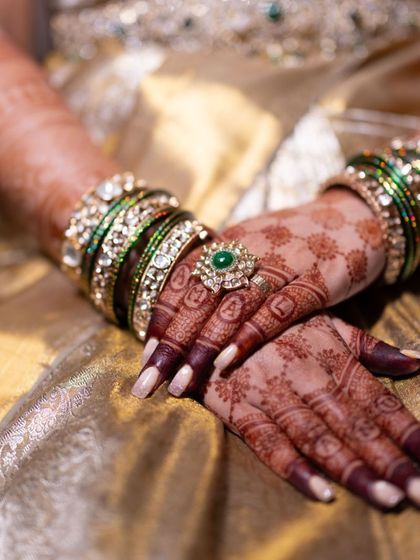 A creative way to include the couple's names. Here, the names Amal and Anusha are woven into a grid pattern on the back of the hands, blending seamlessly with the design.