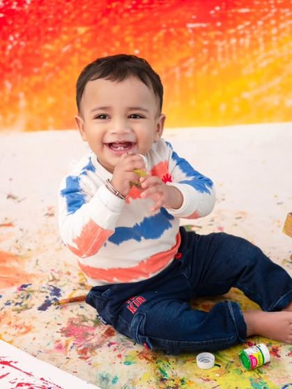 A smile covered in paint! The colorful, abstract background and the joy on his face make this a true masterpiece.