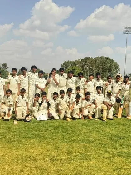 The full U-12 boys squad with their coaches, celebrating a day of competitive cricket.