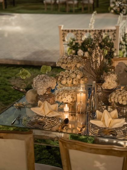 A close-up of the 'Sheesh Mahal' dining setup, with mirrored tables, elegant place settings, and all-white floral arrangements.