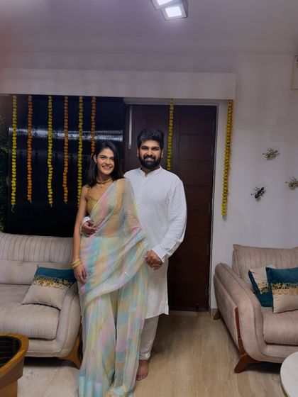 A Diwali celebration photo with my husband. I'm wearing a delicate pastel rainbow saree with a gold blouse, a soft and modern take on festive wear. He complements my look in a simple white kurta.