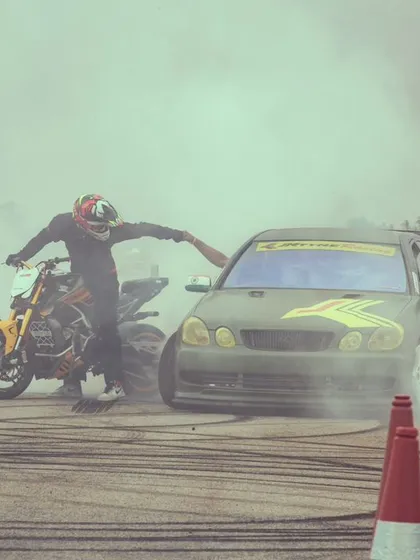 A stunt rider and a drift car create a massive cloud of smoke, a signature moment of our stunt shows. The smell of burning rubber is the smell of excitement.