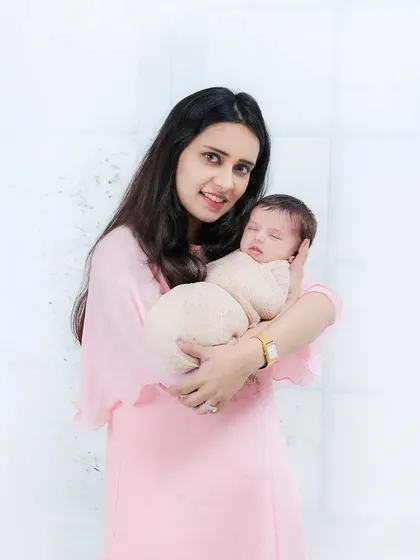 A beautiful portrait of a new mother in a soft pink dress holding her peacefully sleeping newborn. A memory of those quiet, early days.